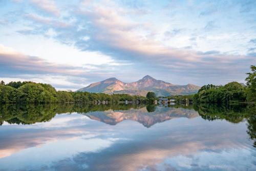 a reflection of a mountain in a lake at Lakeside Hotels Kuore in Kitashiobara
