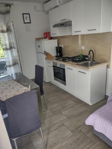 a kitchen with white cabinets and a sink and a table at Apartments Lana in Starigrad