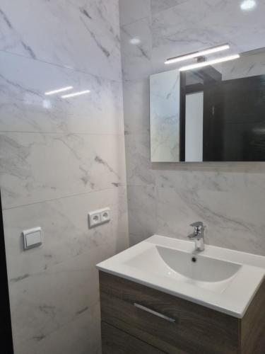 a white bathroom with a sink and a mirror at Appartement Al hoceima in Al Hoceïma