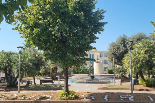 un parque con un árbol y bancos y un edificio en Appartement idéal pour découvrir le Sud d'Italie, en Nova Siri Marina