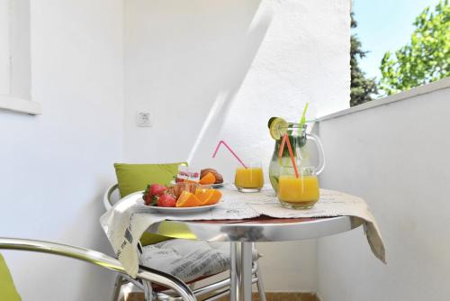 una mesa con un bol de fruta y una jarra de zumo de naranja en Aspalathos dream apartment, en Split