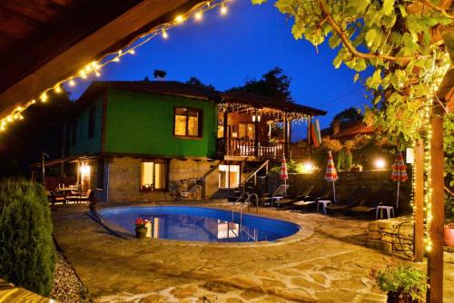 a house with a swimming pool at night with lights at Къща край реката/ House by the river in Vetrintsi