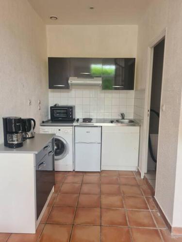 Il comprend une cuisine avec des appareils électroménagers blancs et du carrelage. dans l'établissement Maison dans le centre historique de tréguier, à Tréguier