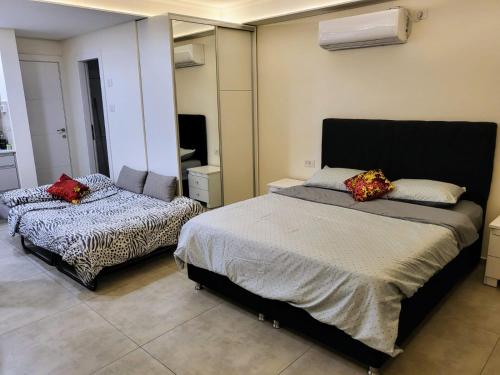 a bedroom with two beds and a mirror at coral suite new vacation apartment in Eilat