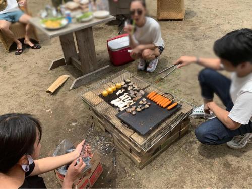a group of people sitting around a table cooking food at Enfield一宮 in Ichinomiya