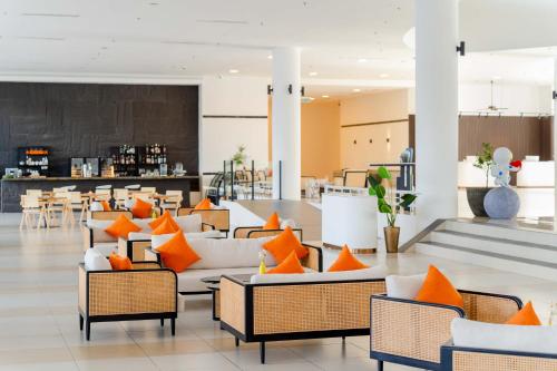 a lobby with orange and white chairs and tables at Wings by Croske Resort Langkawi in Pantai Cenang