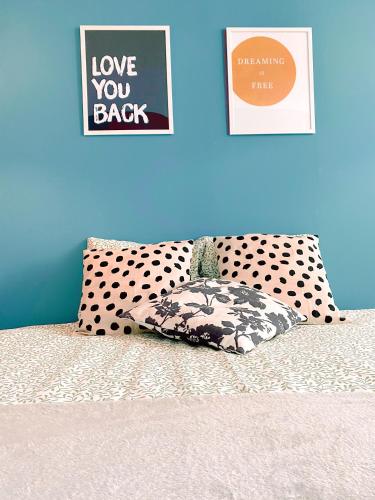 a bed with a polka dot pillow and a wall with posters at Villa do Sol Carcavelos Beach House in Carcavelos