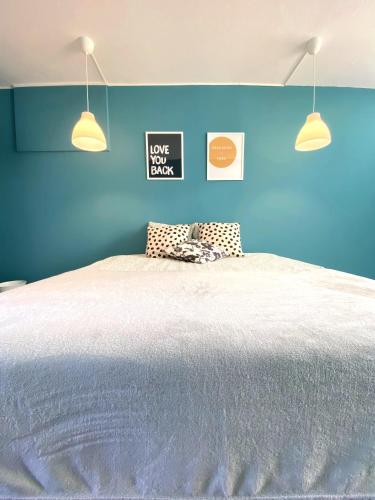 a blue bedroom with a large bed with two lights at Villa do Sol Carcavelos Beach House in Carcavelos