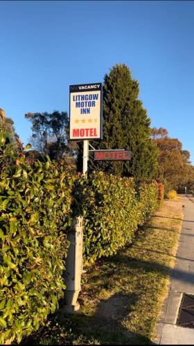 a sign in front of a hedge with a street sign at Lithgow Motor Inn in Lithgow