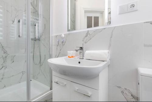 a white bathroom with a sink and a shower at Apartament Hexagon nr 10 in Grzybowo