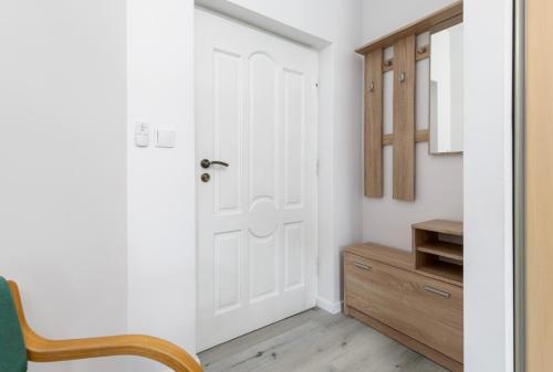 a hallway with a white door and a wooden cabinet at Apartament Hexagon nr 10 in Grzybowo