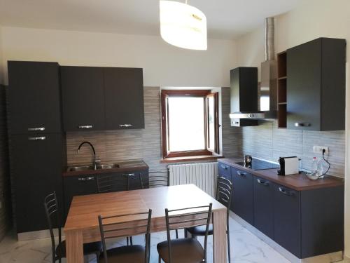 uma cozinha com armários pretos e uma mesa de madeira em Il papavero verde em Lucignano