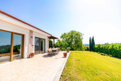 a patio with a table and chairs on a lawn at Villa Bougainvillea in Epanomi