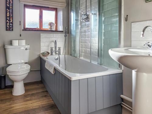 a bathroom with a tub and a toilet and a sink at The Old Byre in Upper Hulme