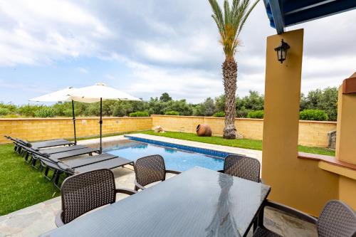 a patio with tables and chairs and a swimming pool at The Olympians Villas in Polis Chrysochous