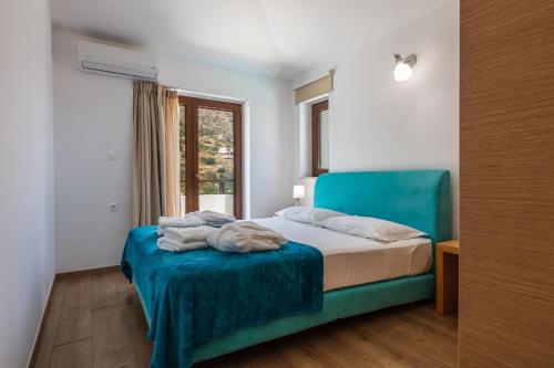 a bedroom with a blue bed and a window at Maris Villas in Elounda