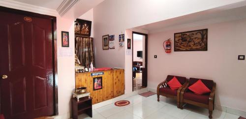 a living room with a door and a chair with red pillows at Ganapathy Garden Homestay in Kodaikānāl
