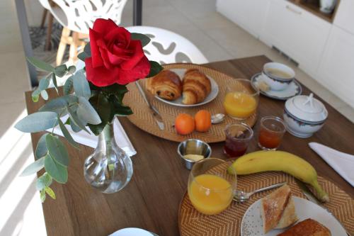 un tavolo con piatti di cibo e un vaso con una rosa di Le Jardin 51 a Andernos-les-Bains
