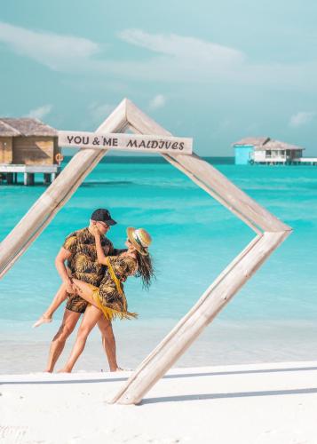 a man and woman walking on the beach at You & Me Maldives - Adults Only - Premium All-Inclusive in Raa Atoll