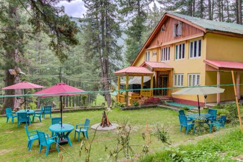 a house in the woods with tables and chairs at Hotel Little Silver in Pahalgām