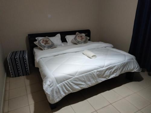 a bed with a white comforter and pillows at Executive 1&2 Broom Airbnb in Gilgil Nakuru in Gilgil