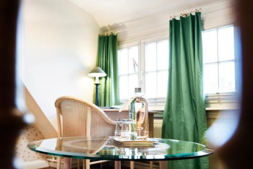 a glass table with two chairs and a green curtain at Romantik Hotel Barbarossa in Konstanz