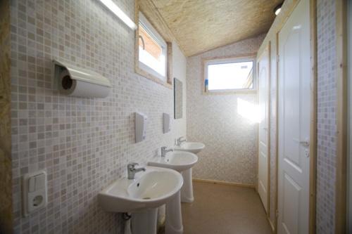 a bathroom with two sinks and two toilets at Kempings Stieres un Mājas Virtuve in Upesgrīva