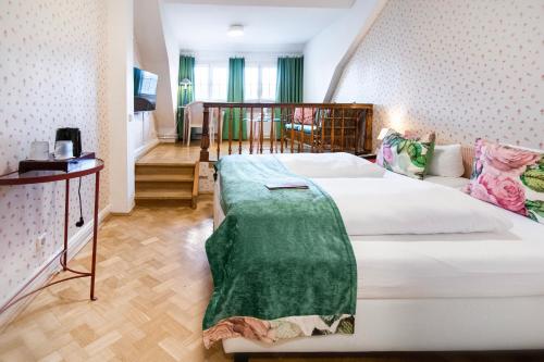 a bedroom with a bed with a green blanket on it at Romantik Hotel Barbarossa in Konstanz