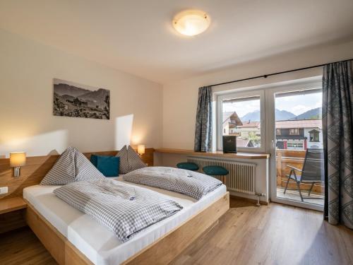 a bedroom with a bed and a large window at Pension Haus in der Sonne in Fieberbrunn