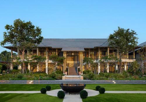 an exterior view of a large house with a fountain at Charras Bhawan Hotel and Residences in Hua Hin