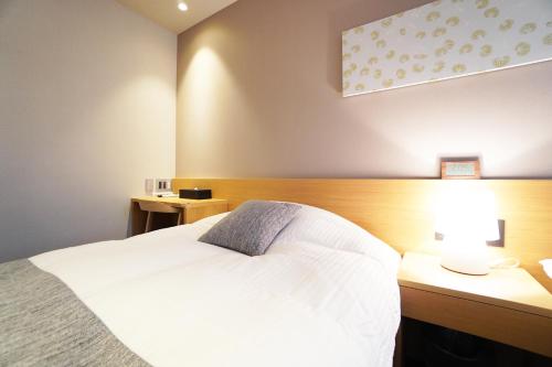 Nishinotōindōri的住宿－Avenir Hotel Kyoto，卧室配有白色的床和带台灯的书桌