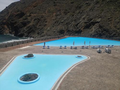 una gran piscina junto a una playa con una montaña en Casa Rural Los Chapines en Vallehermoso