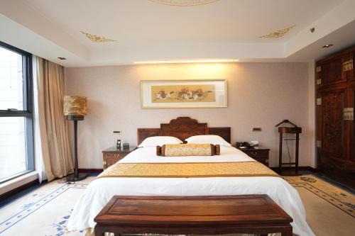 a bedroom with a large bed with a wooden headboard at Chengde Imperial Palace Hotel in Chengde
