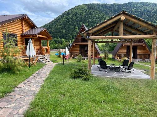 a log cabin with a patio and chairs in the grass at Eco House Borjomi in Borjomi