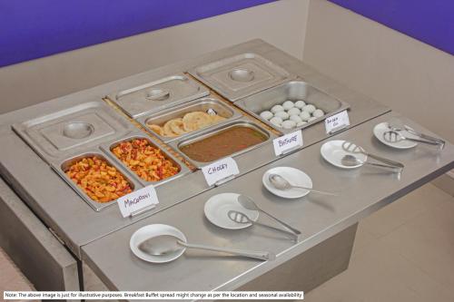 Un buffet con cuencos de comida, platos y cucharas. en Treebo Backpackers Inn, en Kochi