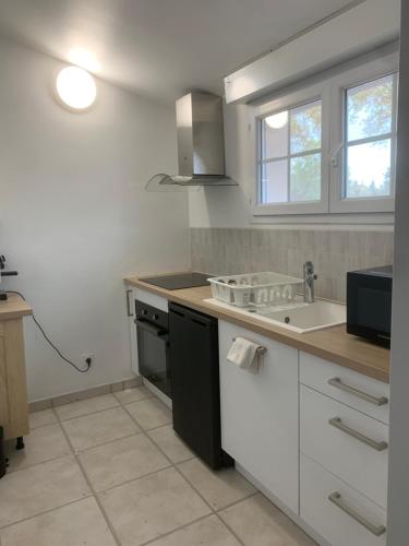 une cuisine blanche avec un évier et une cuisinière dans l'établissement Appartement 4 personne à Rouffiac tolosan, à Rouffiac-Tolosan