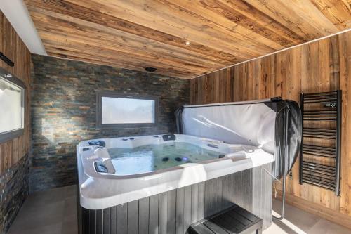 Cette chambre dispose d'une grande baignoire et d'un plafond en bois. dans l'établissement Le Clos du Chêne, maison avec sauna, spa et piscine, à Hadol