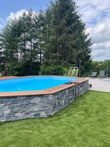- une piscine dans une cour dotée d'un mur en pierre dans l'établissement Le Clos du Chêne, maison avec sauna, spa et piscine, à Hadol