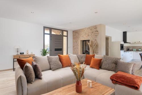 a living room with a large couch with orange pillows at Le Clos du Chêne, maison avec sauna, spa et piscine in Hadol