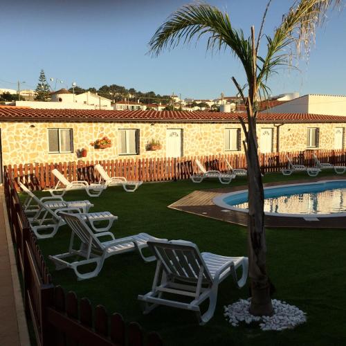 a group of chairs and a palm tree next to a pool at NorthSpot in Nazaré