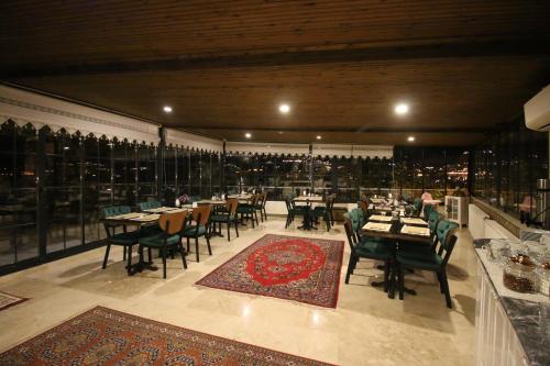 a restaurant with tables and chairs and a large room with windows at Roc Of Cappadocia in Göreme