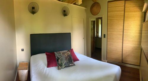1 dormitorio con 1 cama con sábanas blancas y almohadas rojas en Gîte Pont-à-Mousson, La Pépinière Pagode Asiatique, en Pont-à-Mousson
