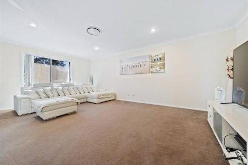 sala de estar blanca con sofás y TV en Halfway Point Brisbane and Gold Coast Themepark 15 minutes Southbank 30 minutes, en Beenleigh