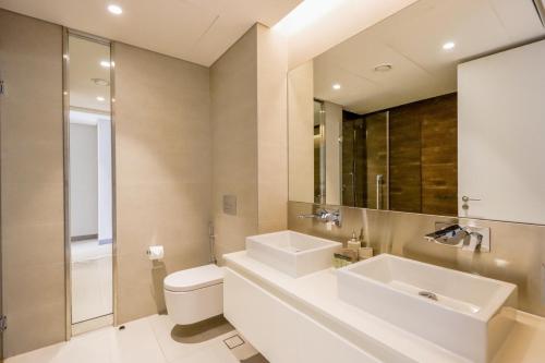 a bathroom with a sink and a toilet and a mirror at Bluewaters Island - High-Floor 1 Bedroom Suite by Livbnb in Dubai