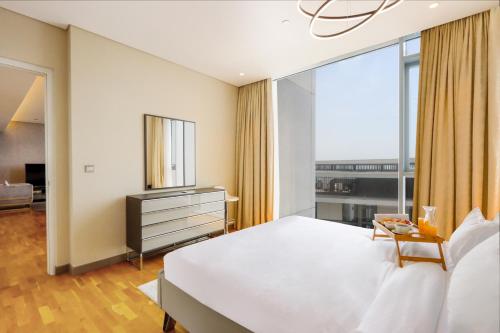 a bedroom with a large white bed and a window at Bluewaters Island - High-Floor 1 Bedroom Suite by Livbnb in Dubai