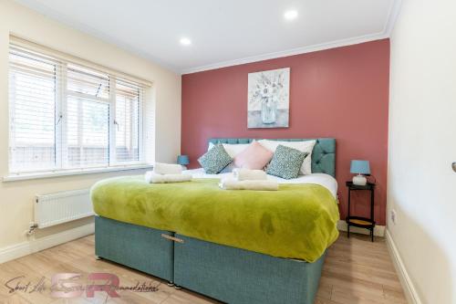 a bedroom with a large bed with red walls at Stylish One Bed House with Private Garden and Free Parking in Northolt