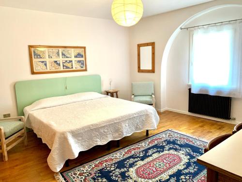 1 dormitorio con cama, ventana y alfombra en MICASA ESTUCASA slow holiday, en Padergnone