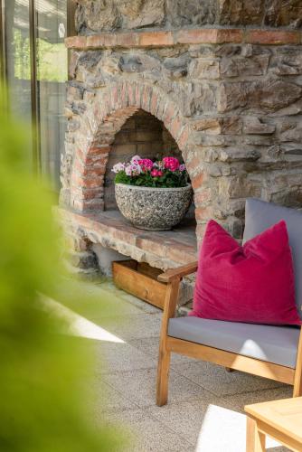 a stone fireplace with a chair and a pot of flowers at Hotel Villa Lago Garni in Bad Wiessee