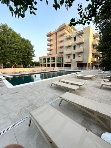 a swimming pool with benches in front of a building at Hotel St Gregory Park in Rimini