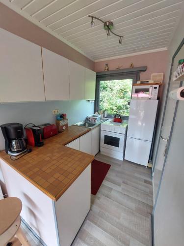 a small kitchen with white cabinets and a window at LE PETIT CHALET - Bungalow in Waulsort